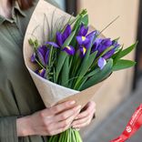Маленькое фото 1: Букет из 7 фиолетовых ирисов с зеленью в крафте