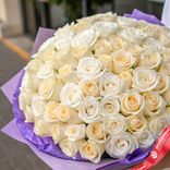 Маленькое фото 2: Букет из 75 белых и кремовых роз в фиолетовой пленке