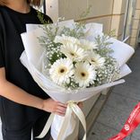 Маленькое фото 3: Букет из 7 белых гербер в белой пленке с белой лентой
