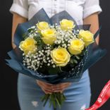 Маленькое фото 1: Букет из 7 желтых роз и 4 белых гипсофил в синей упаковке