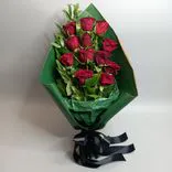 Фото флориста 1: Траурный букет из 12 красных роз в зеленой бумаге