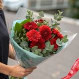 Маленькое фото 1: Букет из 7 красных хризантем и зелени фисташки в стильной пленке «Гранат»